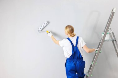 Duvarı evin içinde tekerlekli patenle boyayan kadın işçi, arka manzara. Metin için boşluk