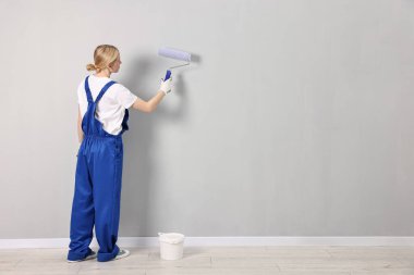 Duvarı evin içinde tekerlekli patenle boyayan kadın işçi, arka manzara. Metin için boşluk