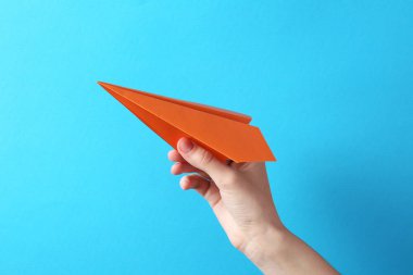 Açık mavi arka planda el yapımı kağıt uçaklı kadın, yakın plan.