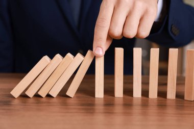 Ahşap blokların masada düşmesini engelleyen adam, yakın plan. Domino etkisi
