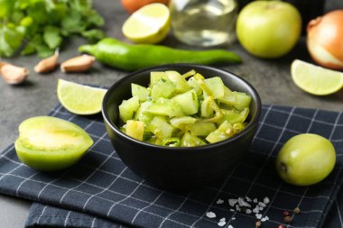 Lezzetli salsa (Pico de gallo) kasede ve gri masada ürünler, yakın plan.