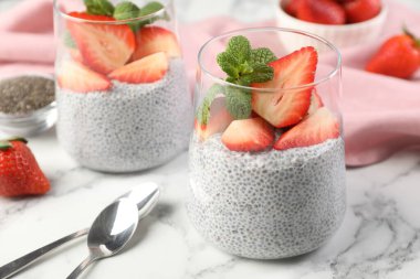 Çilekli lezzetli chia pudingi ve beyaz mermer masada nane şekeri. Yakın plan.