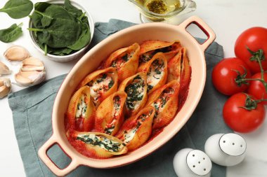 Lezzetli koni makarnası ricotta peyniri, ıspanak ve domates sosu beyaz masada, düz yerde.