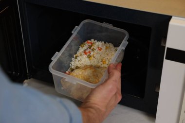 Yemek kabını mikrodalgaya koyan adam, yakın plan.