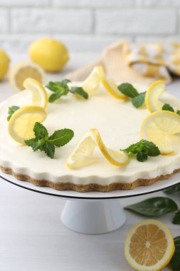 Lezzetli limonlu cheesecake ve beyaz ahşap masada taze meyveler, yakın plan.