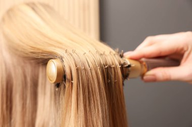 Kuaför, kuaför kuaförü kuaföründe müşterinin saçını tarıyor.