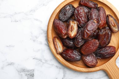 Beyaz mermer masa üzerinde bir sürü lezzetli kurutulmuş hurma, üst manzara. Metin için boşluk