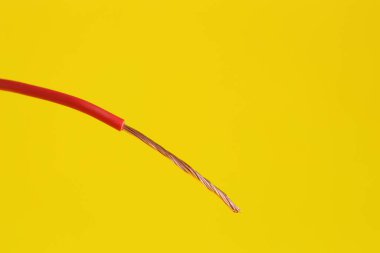 Sarı arka planda kırmızı şeritli elektrik kablosu, yakın plan.