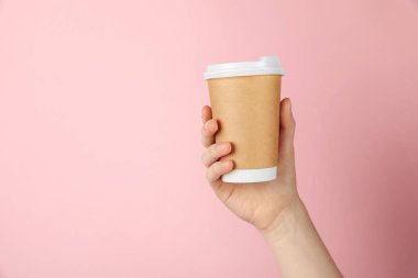 Pembe arka planda kağıt bardak tutan kadın, yakın plan. Tasarım için model