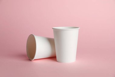 Pembe arka planda kağıt bardaklar. Tasarım için model