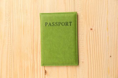 Yeşil kapaklı pasaport, ahşap masa, üst manzara.