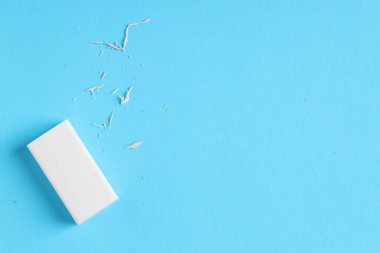 Açık mavi arka planda bir silgi ve kırıntılar, üst manzara. Metin için boşluk