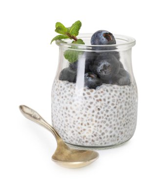 Bardakta yaban mersini, beyaz kaşıkta yaban mersinli lezzetli chia pudingi.