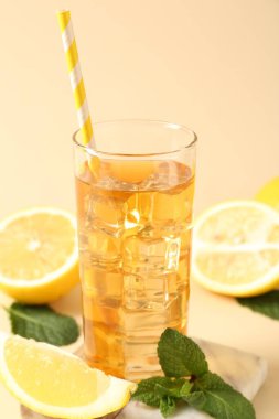 Buzlu çayı tazeleyerek bardakta pipet, bej arka planda nane ve limon içerek yakın plan