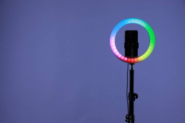 Mor arkaplanda akıllı telefonu olan halka lambası, metin için boşluk