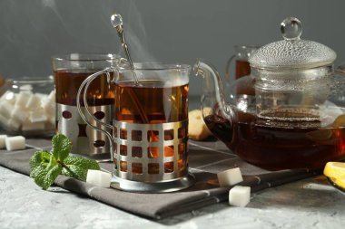 Gri desenli masada servis edilen metal tutacaklı çay bardakları.