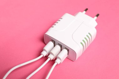 Pembe arka planda şarj kabloları olan USB güç adaptörü, kapat