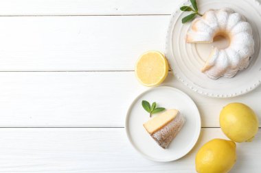 Beyaz ahşap masada pudra şekerli, nane şekerli ve narenciye meyveli lezzetli limonlu pasta. Metin için boşluk