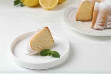 Lezzetli limonlu kek, pudra şekeri ve nane şekeri beyaz ahşap masada.