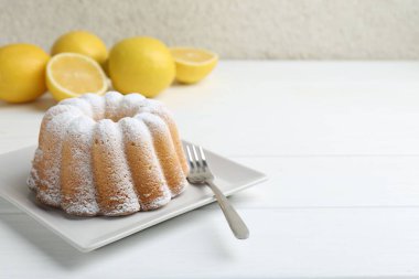 Beyaz ahşap masa üzerinde pudra şekerli ve çatallı lezzetli limonlu pasta, yakın plan. Metin için boşluk