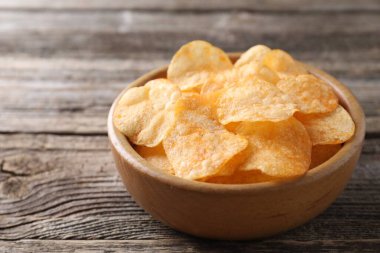 Tahta masadaki kasede patates cipsi, yakın plan. Metin için boşluk