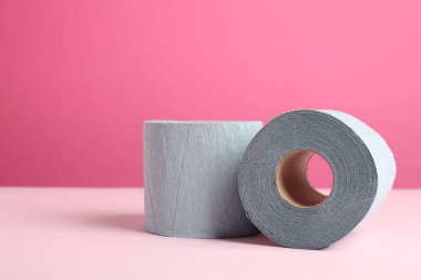 Pembe arka planda mavi tuvalet kağıdı ruloları