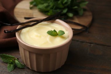 Lezzetli vanilyalı puding, nane ve kapsüller ahşap masada, yakın plan. Metin için boşluk