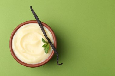 Lezzetli vanilyalı puding, nane ve kapsül yeşil arka planda, üst manzara. Metin için boşluk