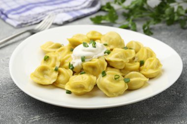 Taze soğanlı ve ekşi kremalı lezzetli hamur tatlısı. Gri desenli masa, yakın plan.