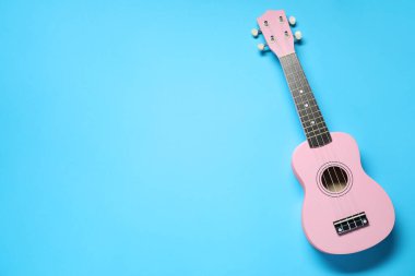 Açık mavi arka planda bir ukulele, üst manzara. Metin için boşluk