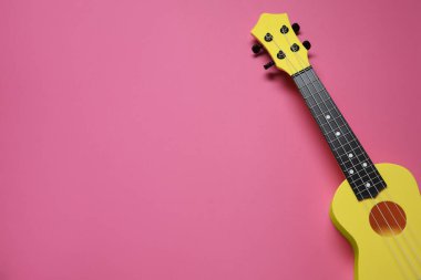 Pembe arka planda bir ukulele, üst manzara. Metin için boşluk