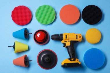 Açık mavi arka planda farklı cila pedleri olan elektrikli tornavida, düz konum