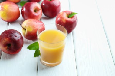 Elma suyunu bardakla tazelemek ve beyaz tahta masada meyveler, yakın plan. Metin için boşluk