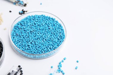 Petri kabında renkli plastik granüller ve beyaz arka planda test tüpleri, yakın plan. Metin için boşluk