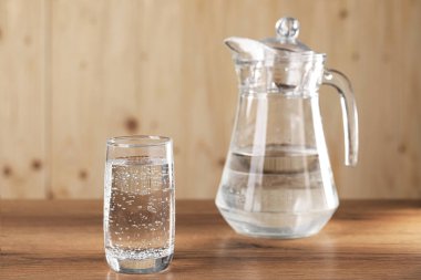 Soda tazeleniyor. Bardakta buz küpleri ve tahta masada sürahi.