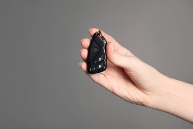 Gri arka planda araba çevirme anahtarı olan kadın, yakın plan. Metin için boşluk