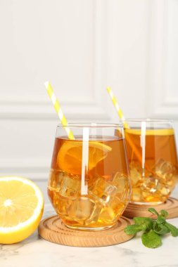 Buzlu çayı limon dilimleriyle, nane şekeriyle ve beyaz mermer masada pipet içerek tazeliyorum.