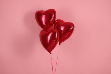 Pembe arka planda üç kırmızı kalp şeklinde balon. Sevgililer Günün kutlu olsun.