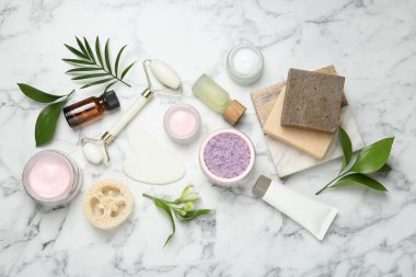 Beyaz mermer masa üzerinde farklı vücut bakım ürünleri ve çiçekler ile düz bileşim yatıyordu