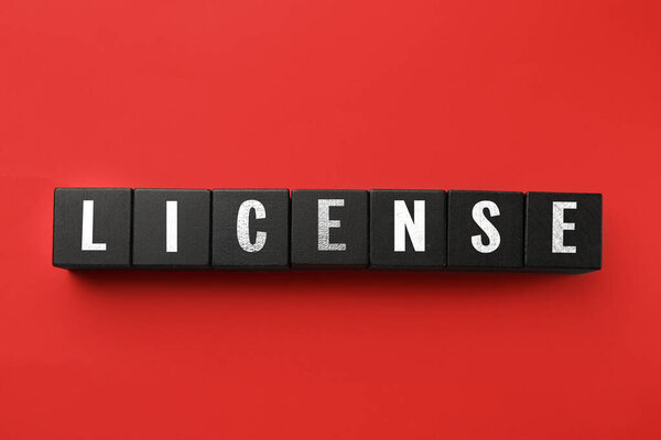 License word made of black cubes with letters on red background, top view