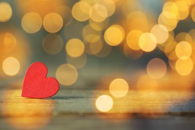 Sevgililer Günü tebrik kartı. Tahta masada küçük kırmızı bir kalp, bokeh etkisi. Metin için boşluk