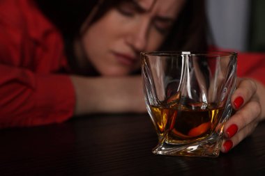 Alkol bağımlılığı. Masasında viski olan zavallı kadın. Karanlık, seçici bir odak noktası.