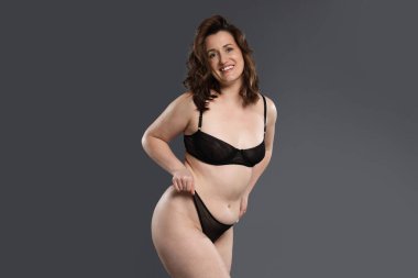 Koyu gri arka planda iç çamaşırlı güzel bir kadın. Selülit problemi