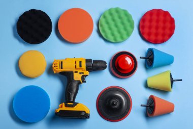 Açık mavi arka planda farklı cila pedleri olan elektrikli tornavida, düz konum