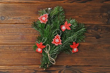 Ahşap arka planda Noel dekoru olan yeşil köknar dallarından oluşan şenlikli bir buket.