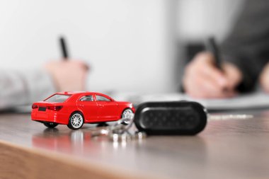 Araba satın alıyorum. Araba modeli ve anahtar ahşap masada, seçici odak