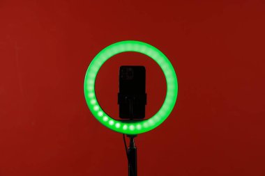 Kırmızı arka planda akıllı telefonu olan halka lambası