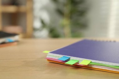 Kapalı alandaki ahşap masada renkli etiketli defter, yakın plan. Metin için boşluk