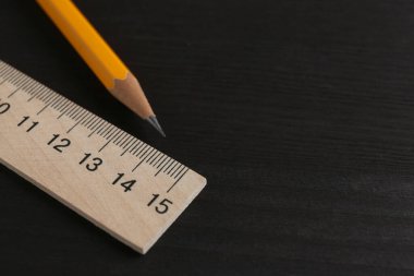 Siyah tahta masadaki cetvel ve kalem, yakın plan. Metin için boşluk