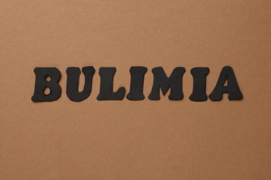Kahverengi arka planda kelime Bulimia, üst görünüm